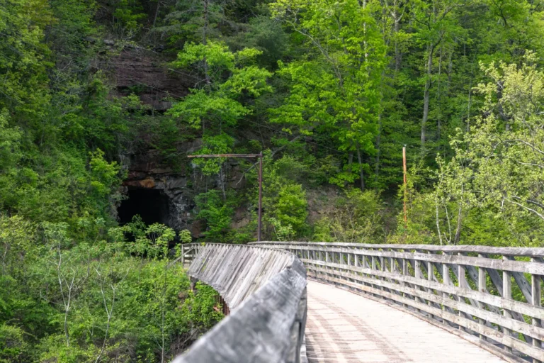 wooden railroad bridge leading to tunnel on rail trail