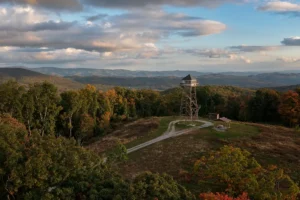 Thorny Mountain Tower-2 - Mon Forest Towns - Mon Forest Towns Wooden observation tower on a hilltop, surrounded by autumn-colored trees with a dirt path and a small shelter nearby.